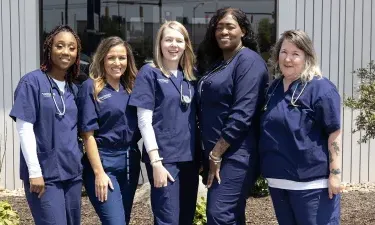 Students from Herzing University’s medical assisting program standing together outdoors.